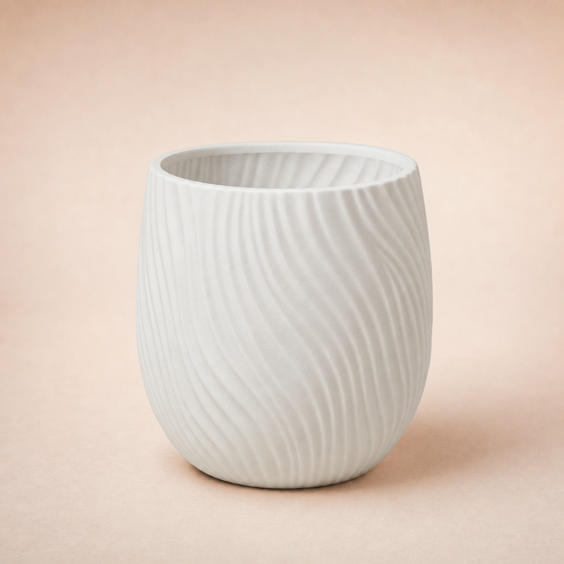 Eén witte designer plantenpot met golfreliëf frontaal op een warme studioachtergrond